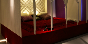 Полутемная спальня с кроватью на красном подиуме: дизайнер Диана Ларина